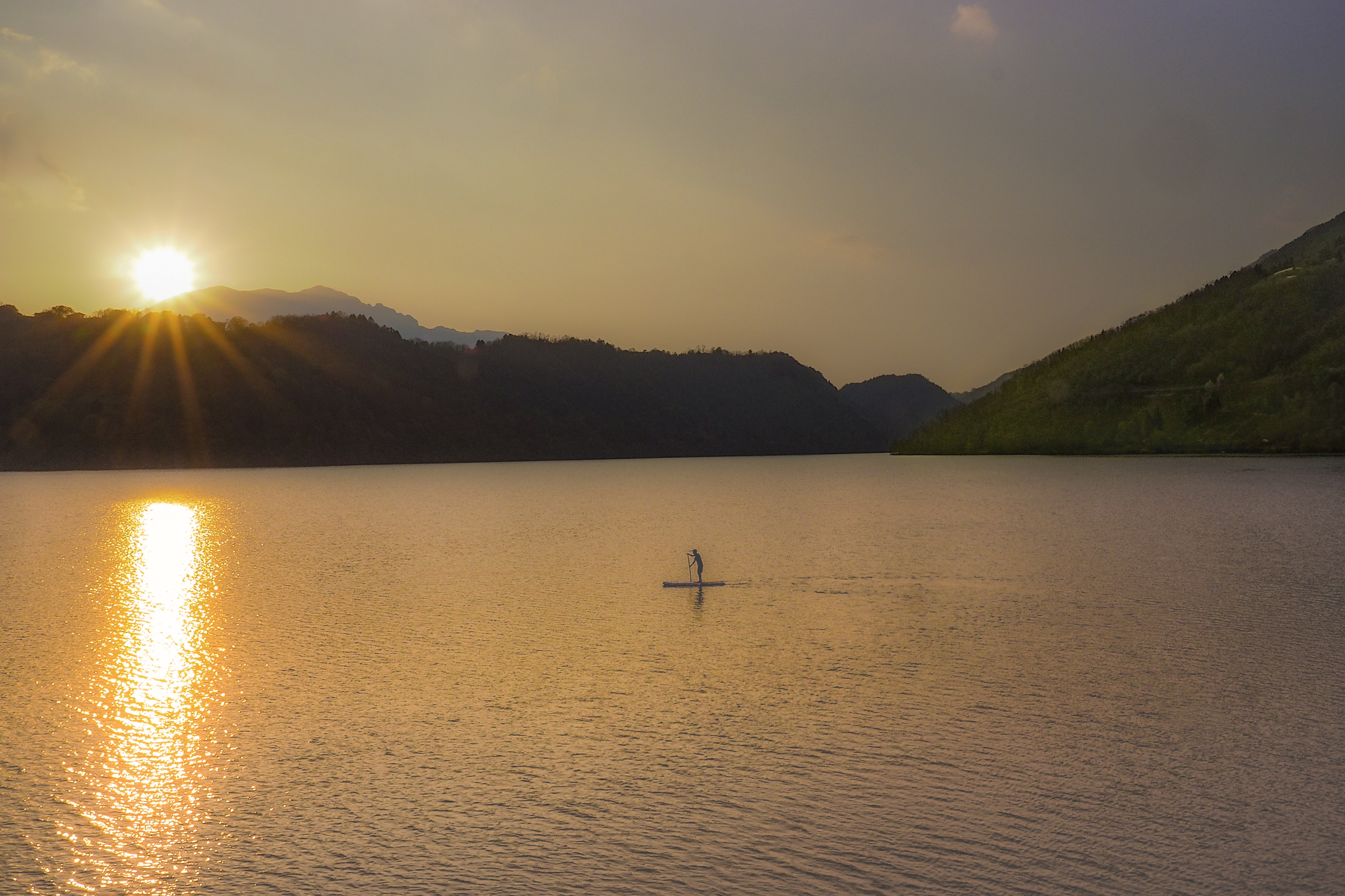 Persona pratica SUP sul lago di Levico in Valsugana al tramonto